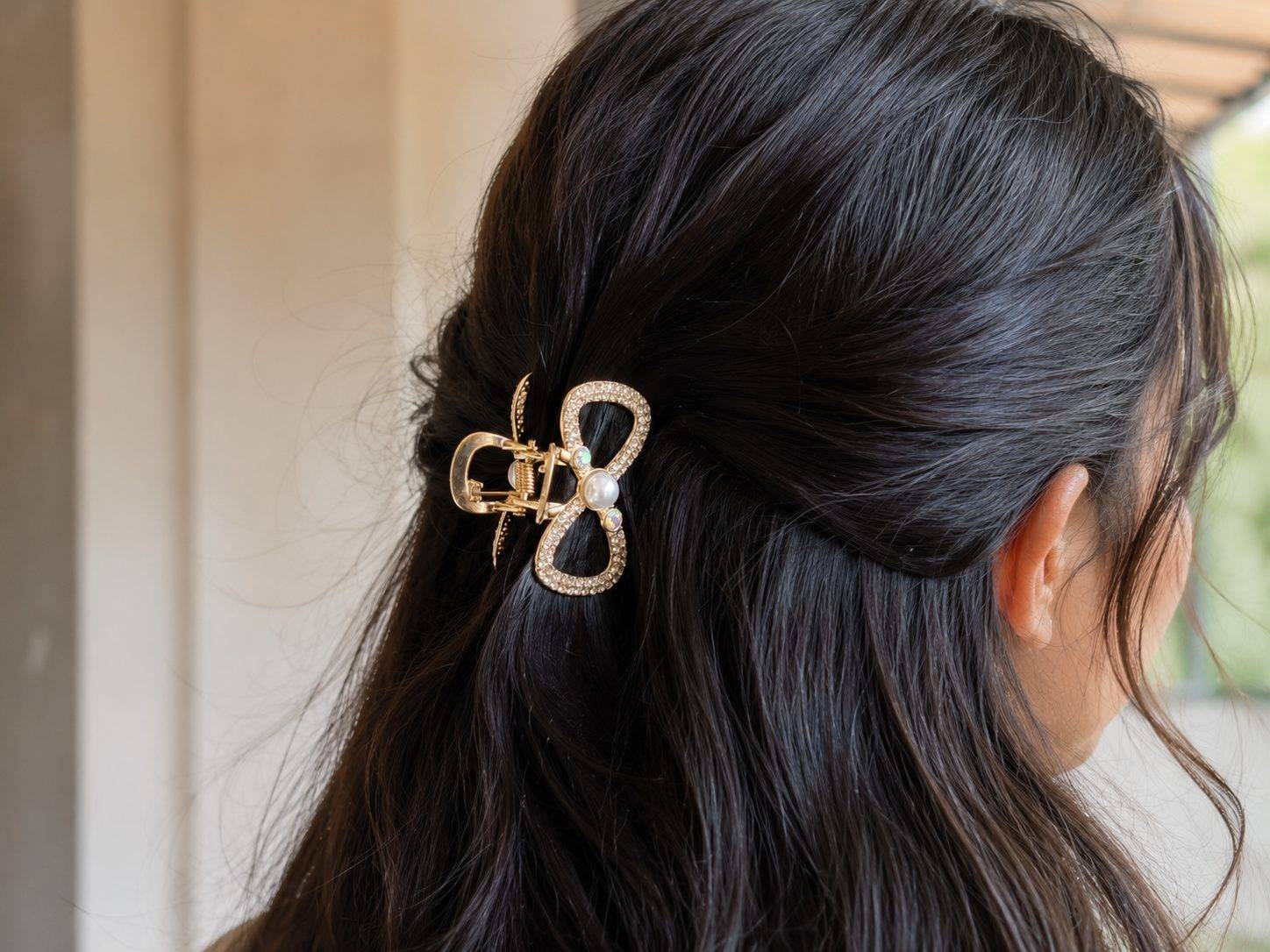 Bow design embellished with rhinestones and a central faux pearl.