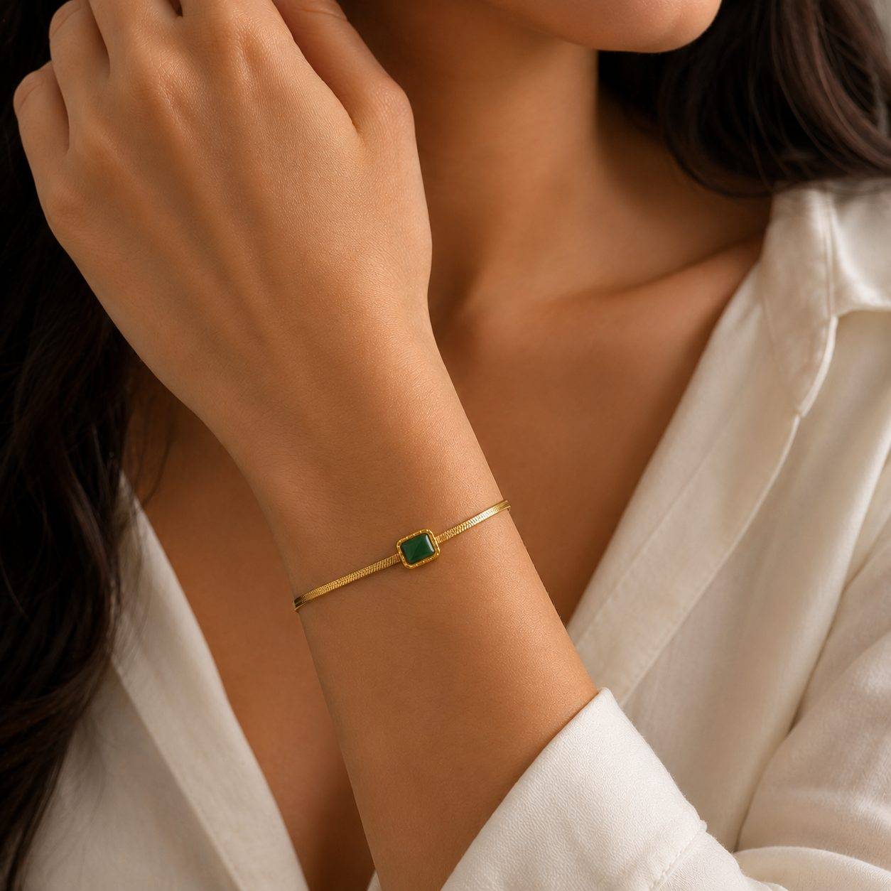 Gold tone snake chain bracelet features a square stone pendant