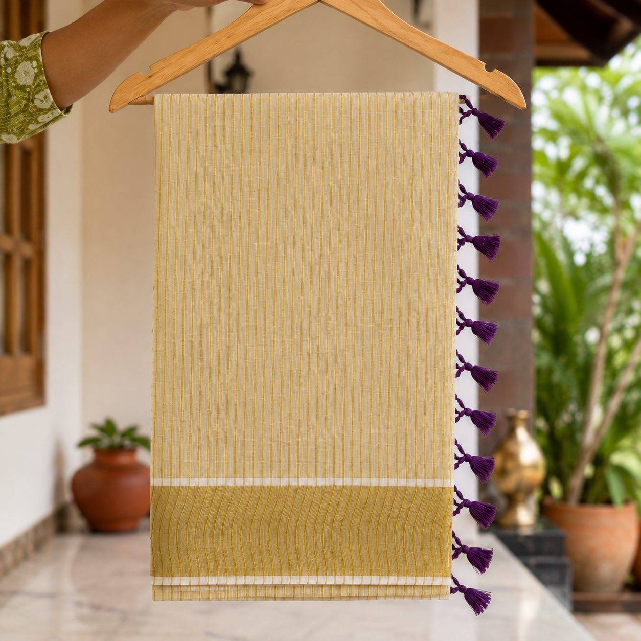 striped mul cotton festive saree featuring a broad golden zari border and decorative red tassel accents