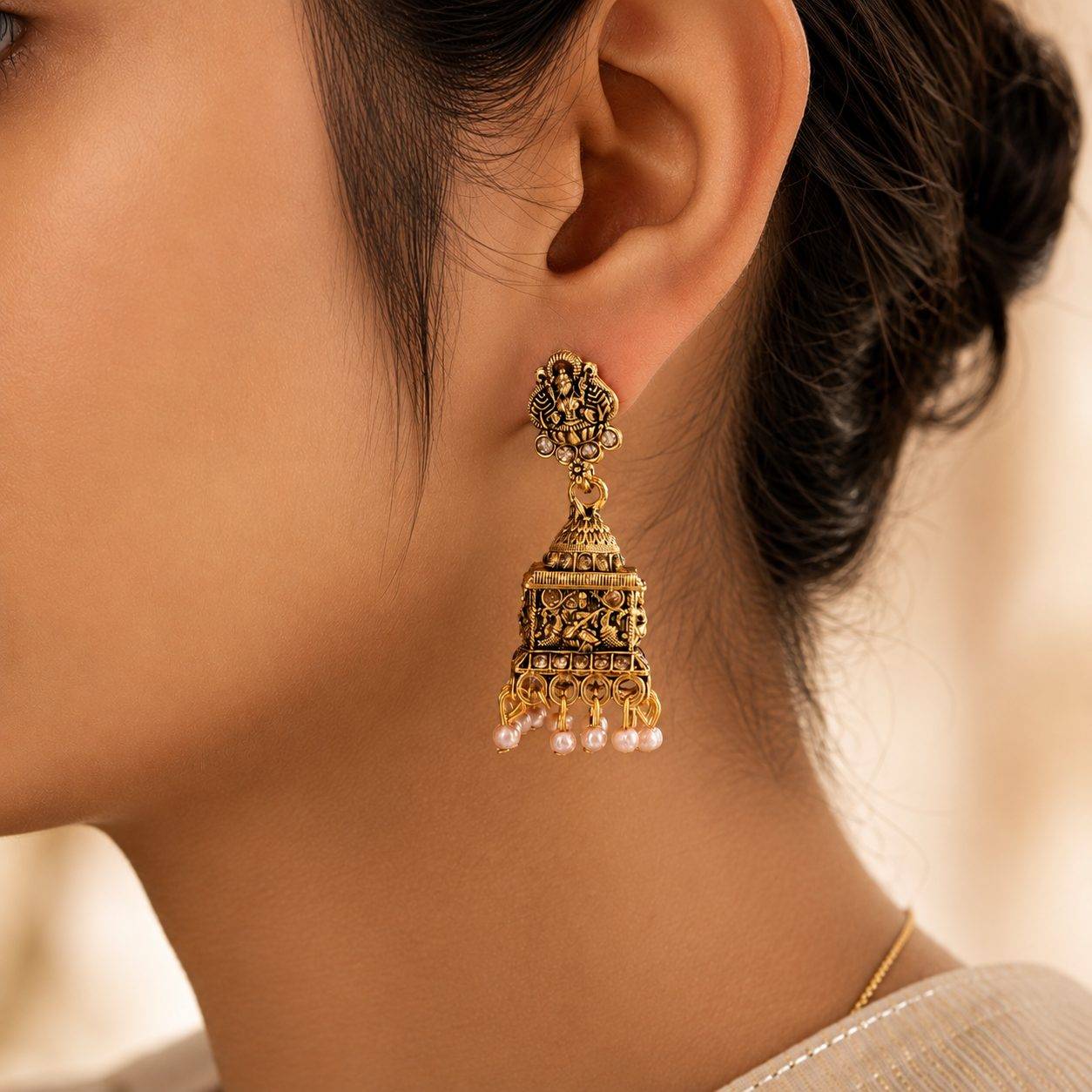 Goddess Lakshmi temple jhumka earrings featuring intricate square-domed motifs and delicate pearl drop hangings.